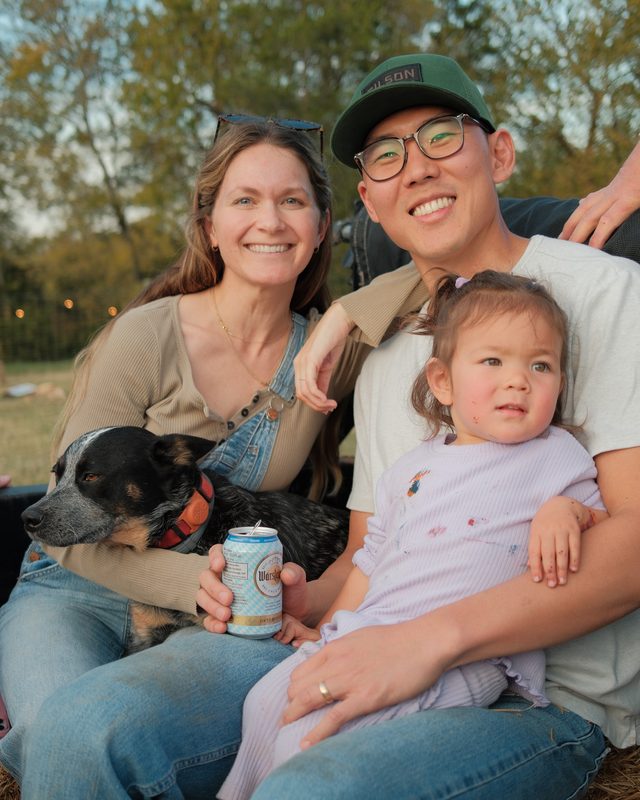 Me with my family and our dog, sitting on hay bales outside at sunset.